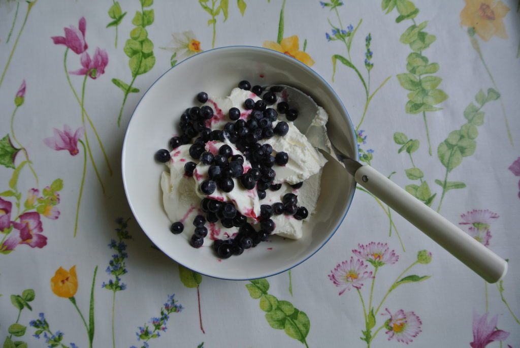 Breakfast consisting of yoghurt, berries and black coffee.