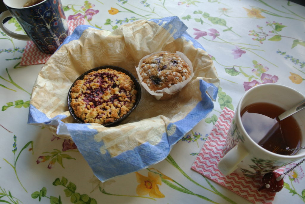 Day off Two cups of tea and muffins on a colorful table cloth