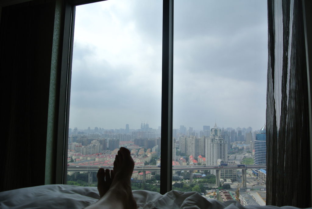 Dear Shanghai A view from a hotel window in China, hotel bed with white sheets, feet