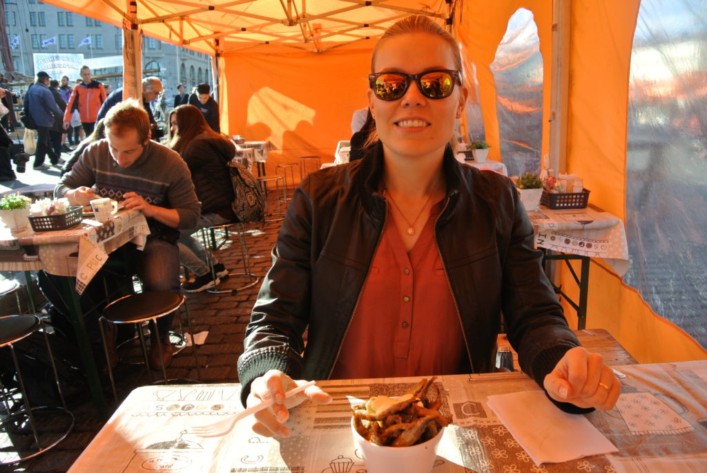 Fish market A happy girl eating fish in the market place in the center of Helsinki