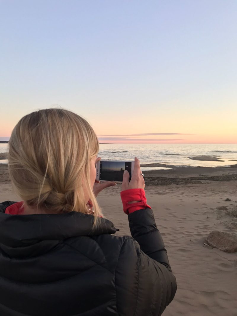 Sunset drive A blonde girl taking pictures of a sunset in Varessäikkä beach in Finland