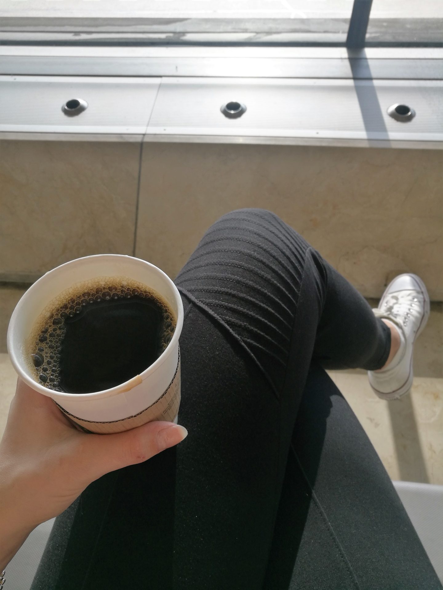Hasta pronto Madrid Annimarian A girl sitting at the airport drinking black coffee