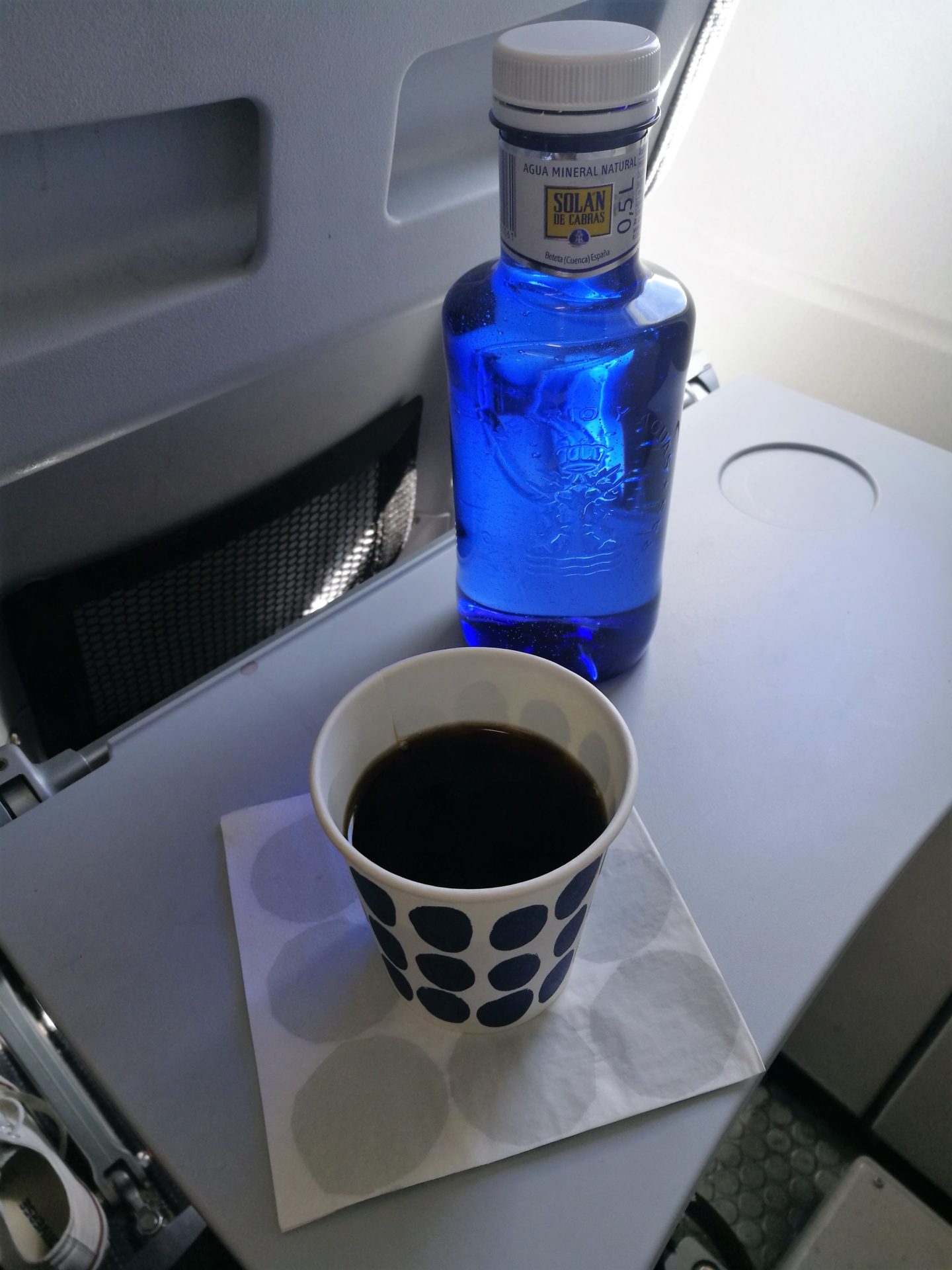 Hasta pronto Madrid Annimarian Black coffee and a water bottle on the table in a Finnair aircraft